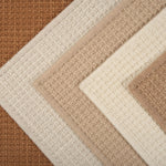 Stack of broadloom carpets in neutral colors. 