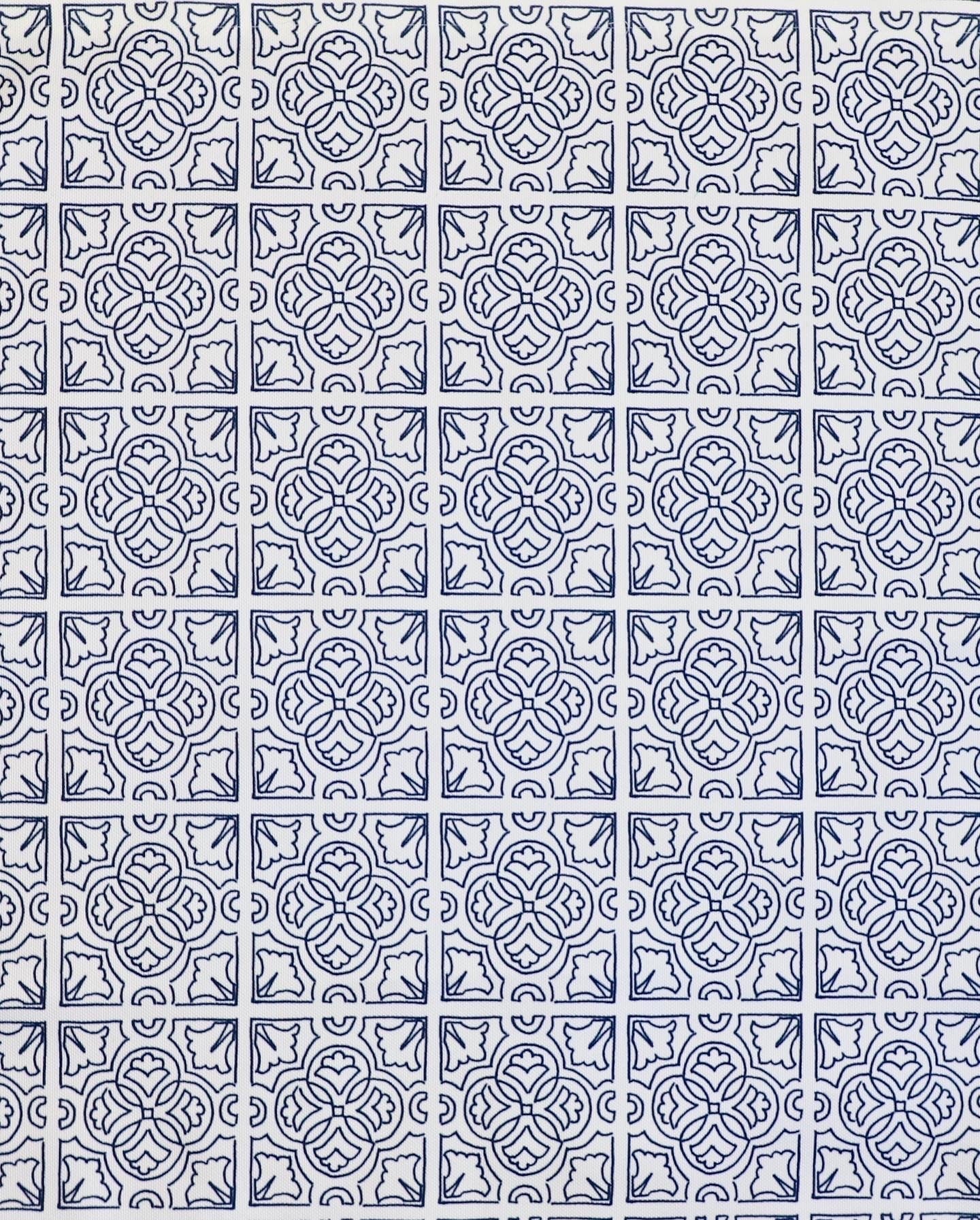 Detail of fabric in a damask lattice print in navy on a white field.