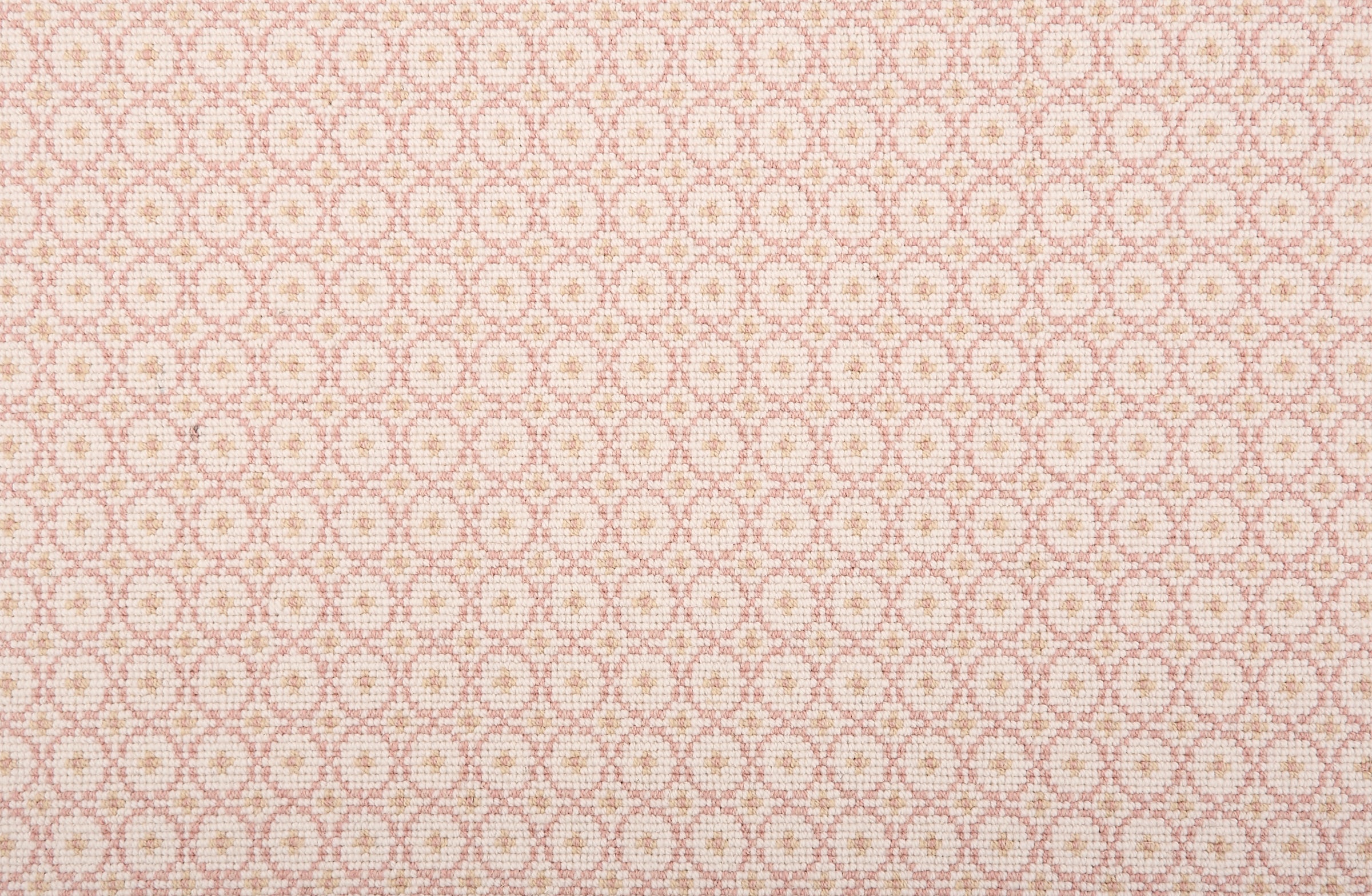 Broadloom carpet in a dense circle lattice with small floral accents in light pink a cream field.