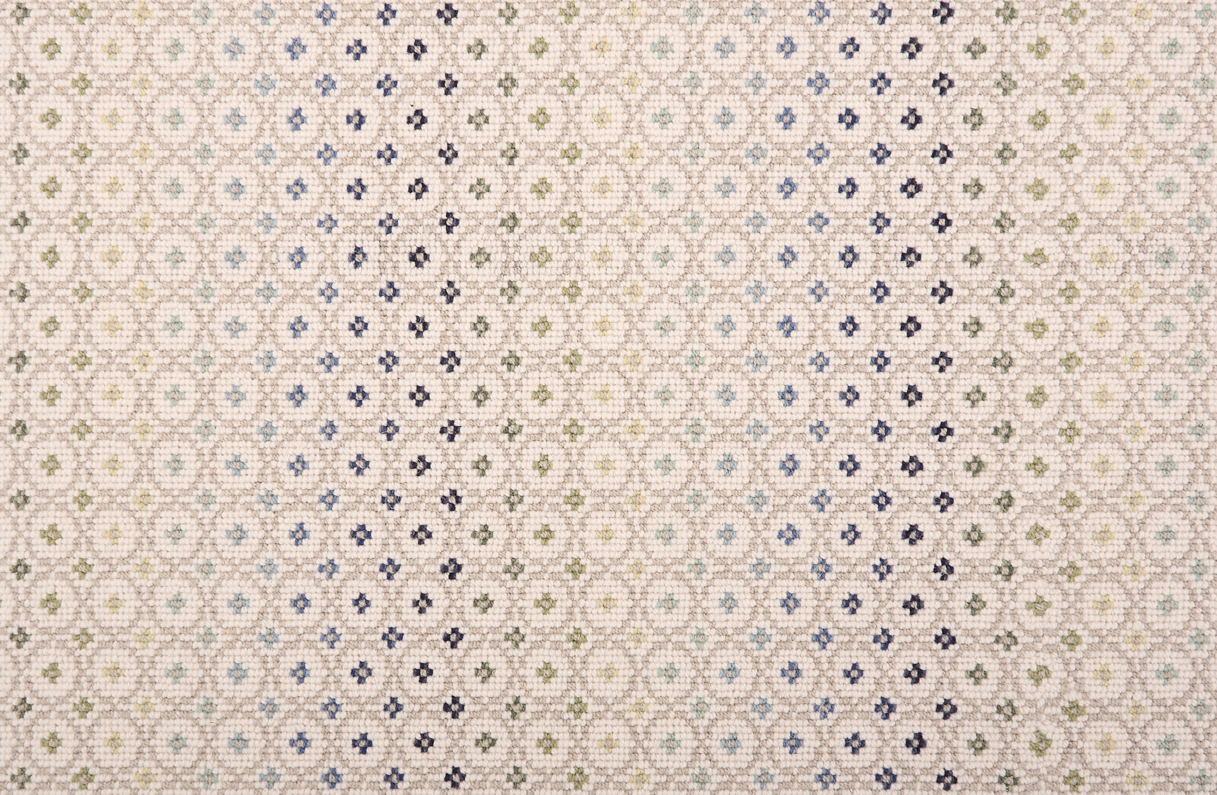 Broadloom carpet in a dense circle lattice with small floral accents in a ombré of green and blue on a cream field.