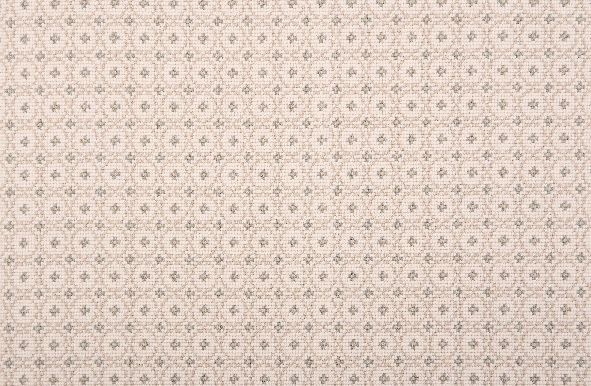 Broadloom carpet in a dense circle lattice with small floral accents in taupe on a cream field.