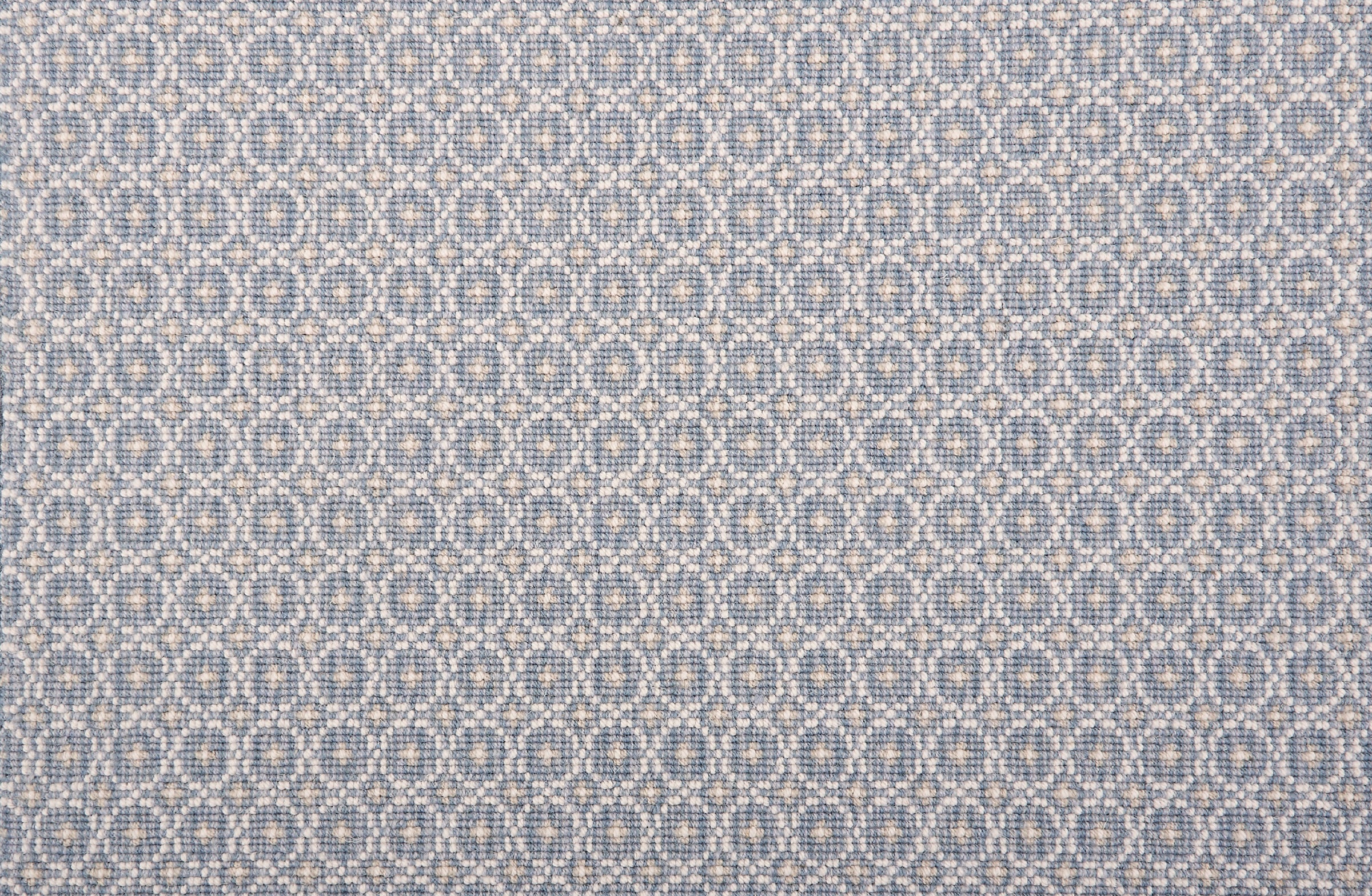 Broadloom carpet in a dense circle lattice with small floral accents in ecru on a blue field.