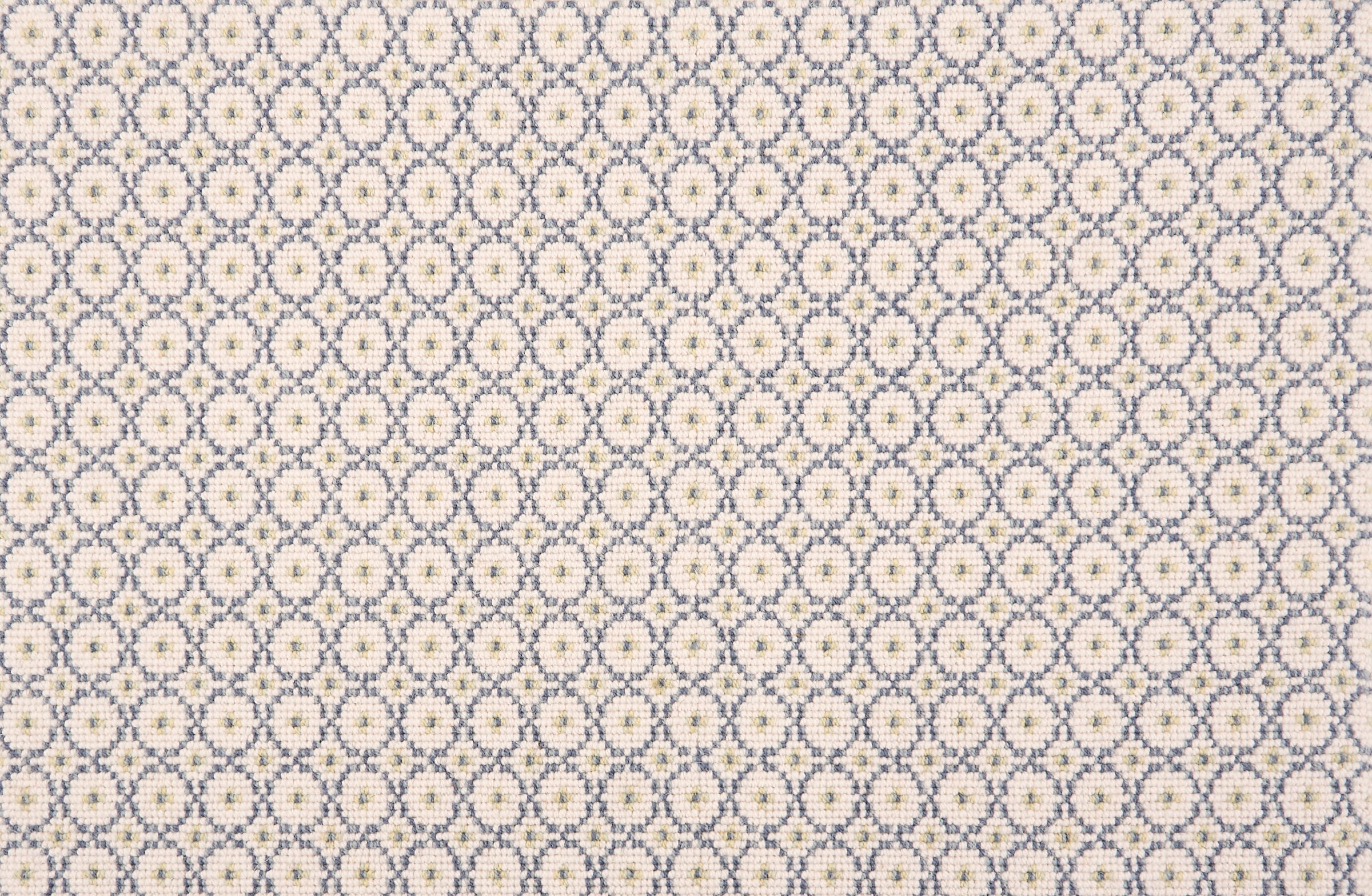 Broadloom carpet in a dense circle lattice with small floral accents in blue and green a cream field.