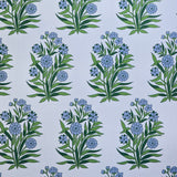 Detail of fabric in a repeating floral print in shades of blue and green on a light blue field.