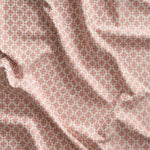 Close up of gently draped woven Indoor-Outdoor fabric with dense floral medallion pattern in coral pink on white. 