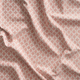 Close up of gently draped woven Indoor-Outdoor fabric with dense floral medallion pattern in coral pink on white. 
