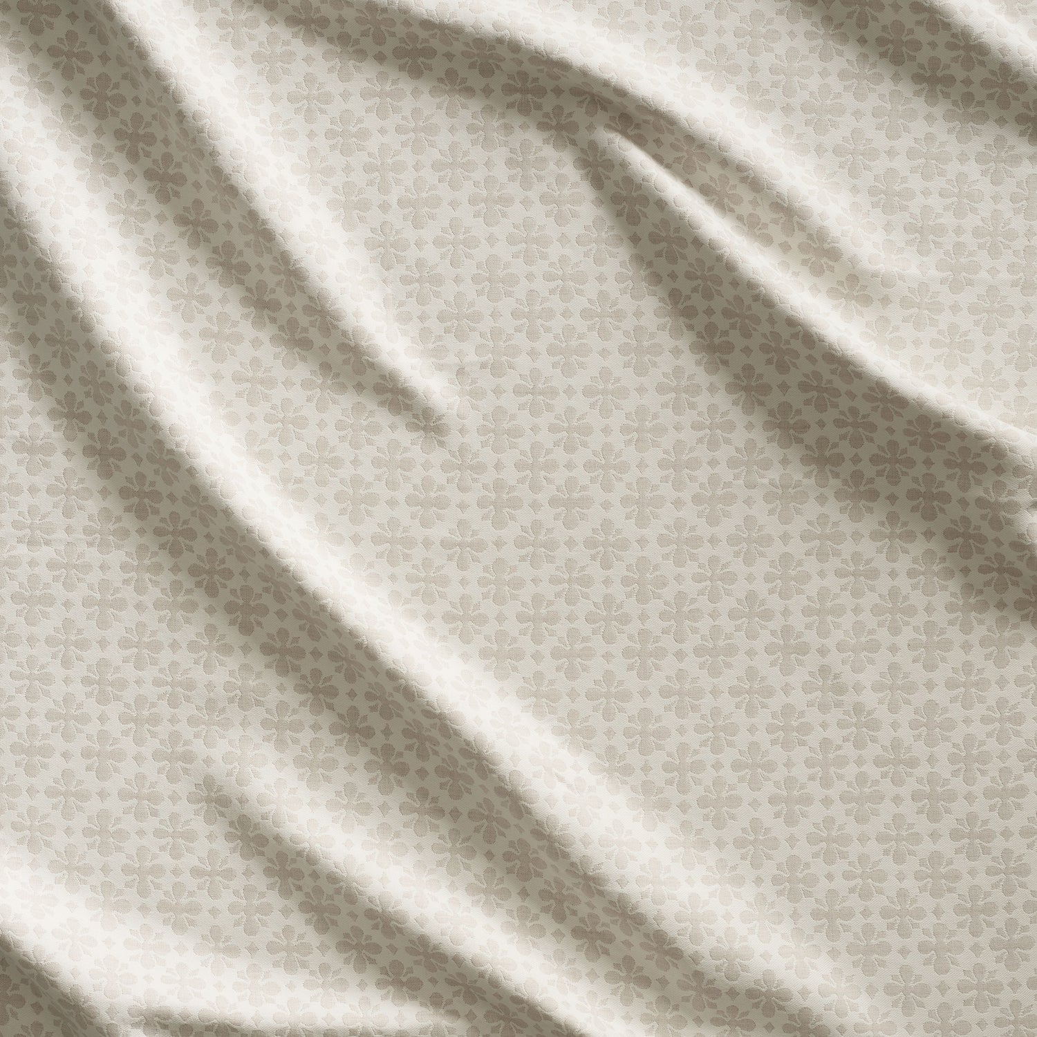 Close up of gently draped woven Indoor-Outdoor fabric with dense floral medallion pattern in beige on white. 
