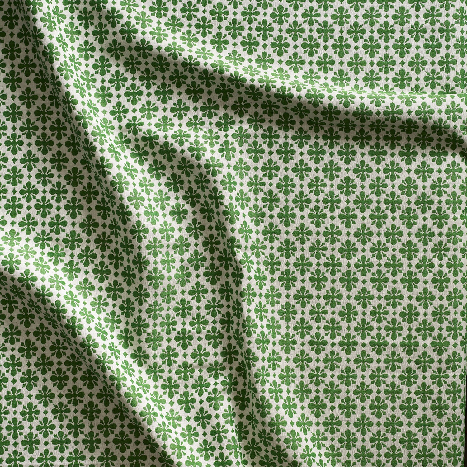 Close up of gently draped woven Indoor-Outdoor fabric with dense floral medallion pattern in grass green on white. 