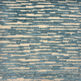 Handknotted rug sample in a textural linear design in turquoise on a cream field.