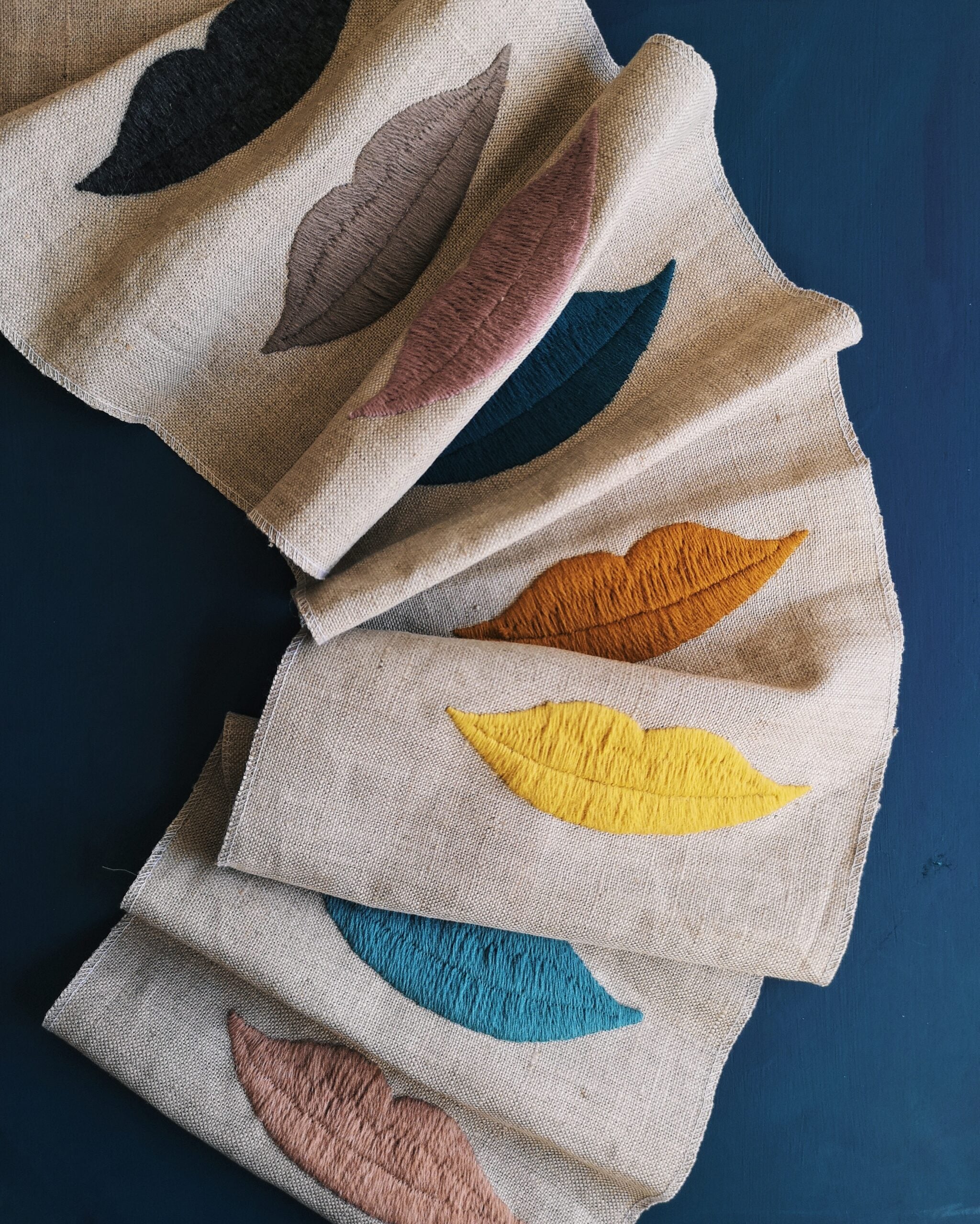 Draped linen with colorful embroidered lips on a blue background. 