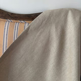 Close-up of a beige fabric draped over a yellow striped sofa.