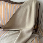 Beige linen draped over a striped chair with a white wall background