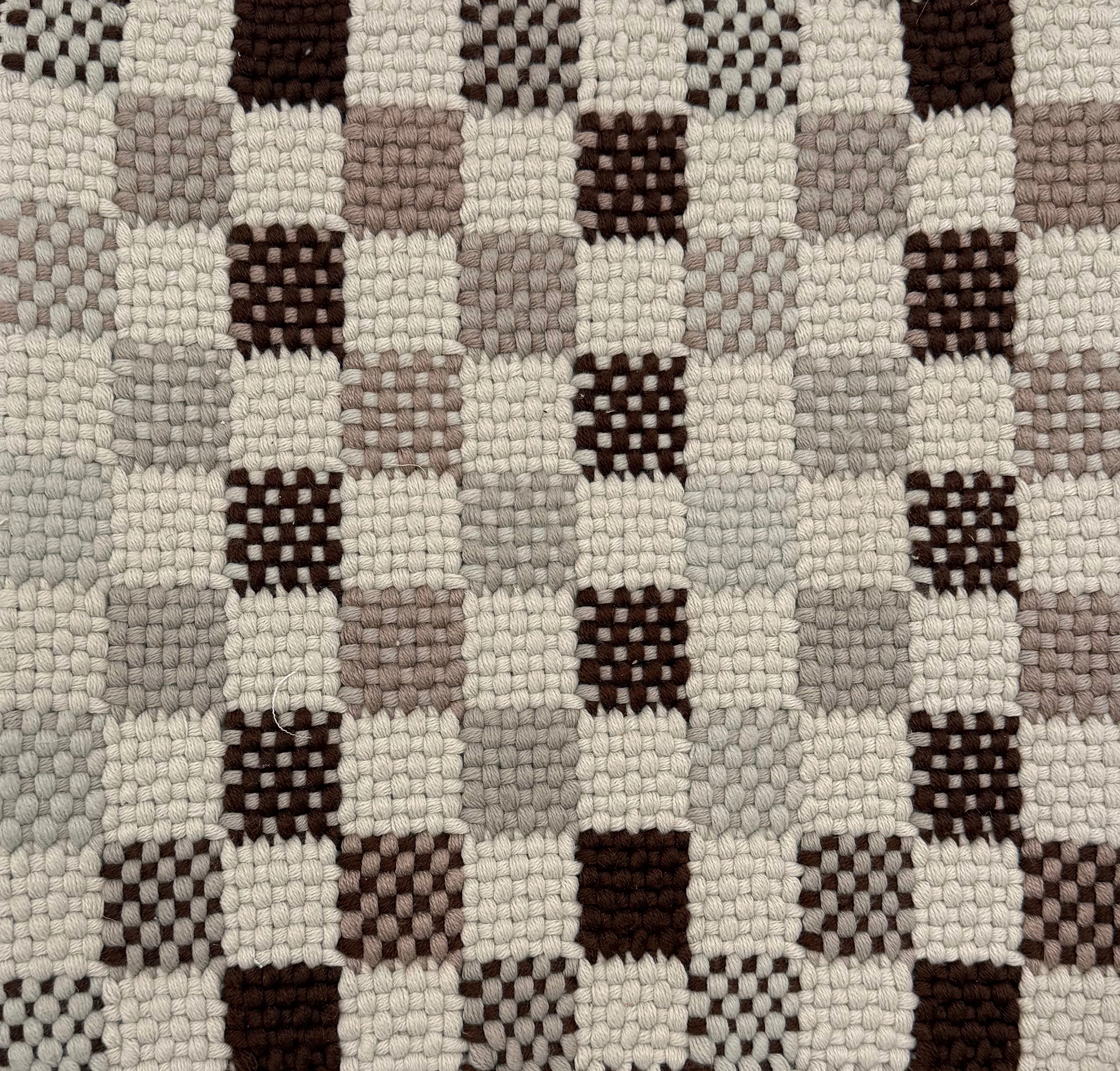 Close-up of a textured checkered rug with brown, gray, and beige squares.