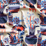 Close up of gently draped fabric in an ornate hand drawn urn and floral pattern in coral and blue on white. 