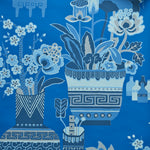 Close up of wallpaper in an ornate hand drawn urn and floral pattern in shades of  bright blue. 