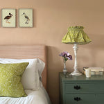 A cozy bedroom tableau with a amp and throw pillows all upholstered in the same scrolling stem and leaf print.