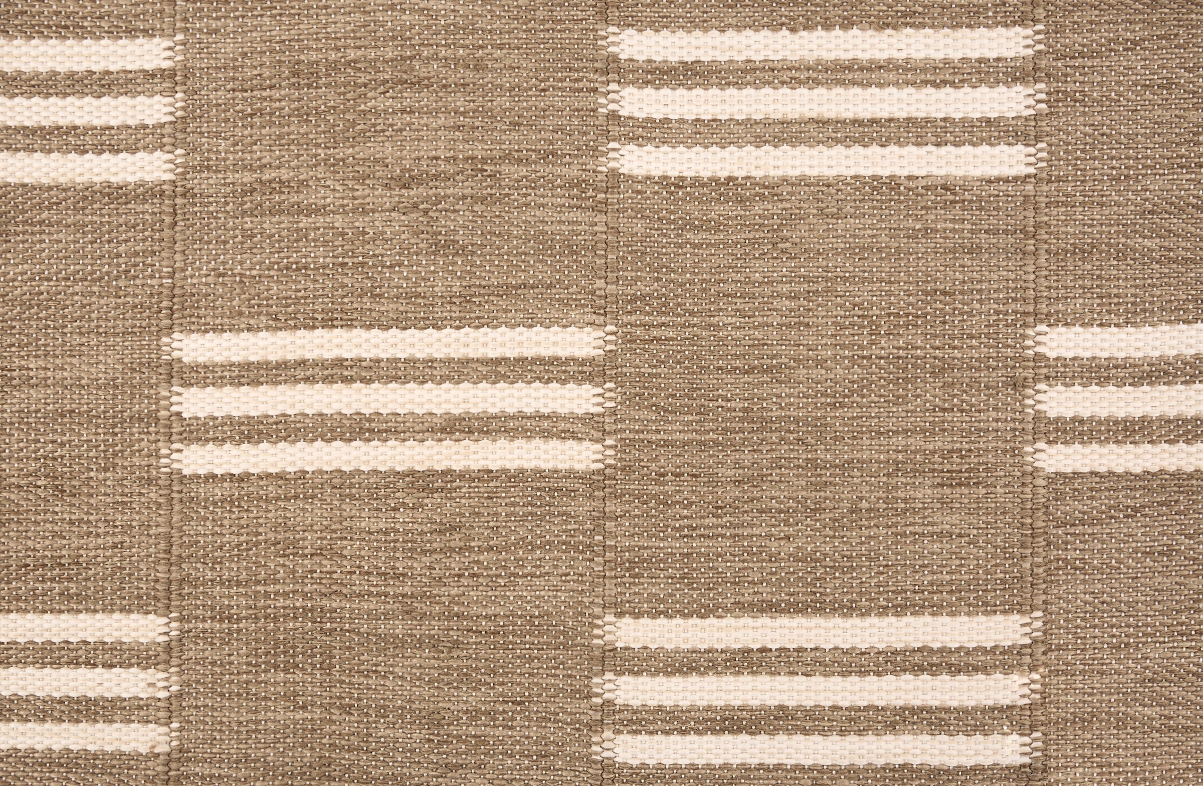 Broadloom flatweave carpet in a broken stripe in white on a brown field. 