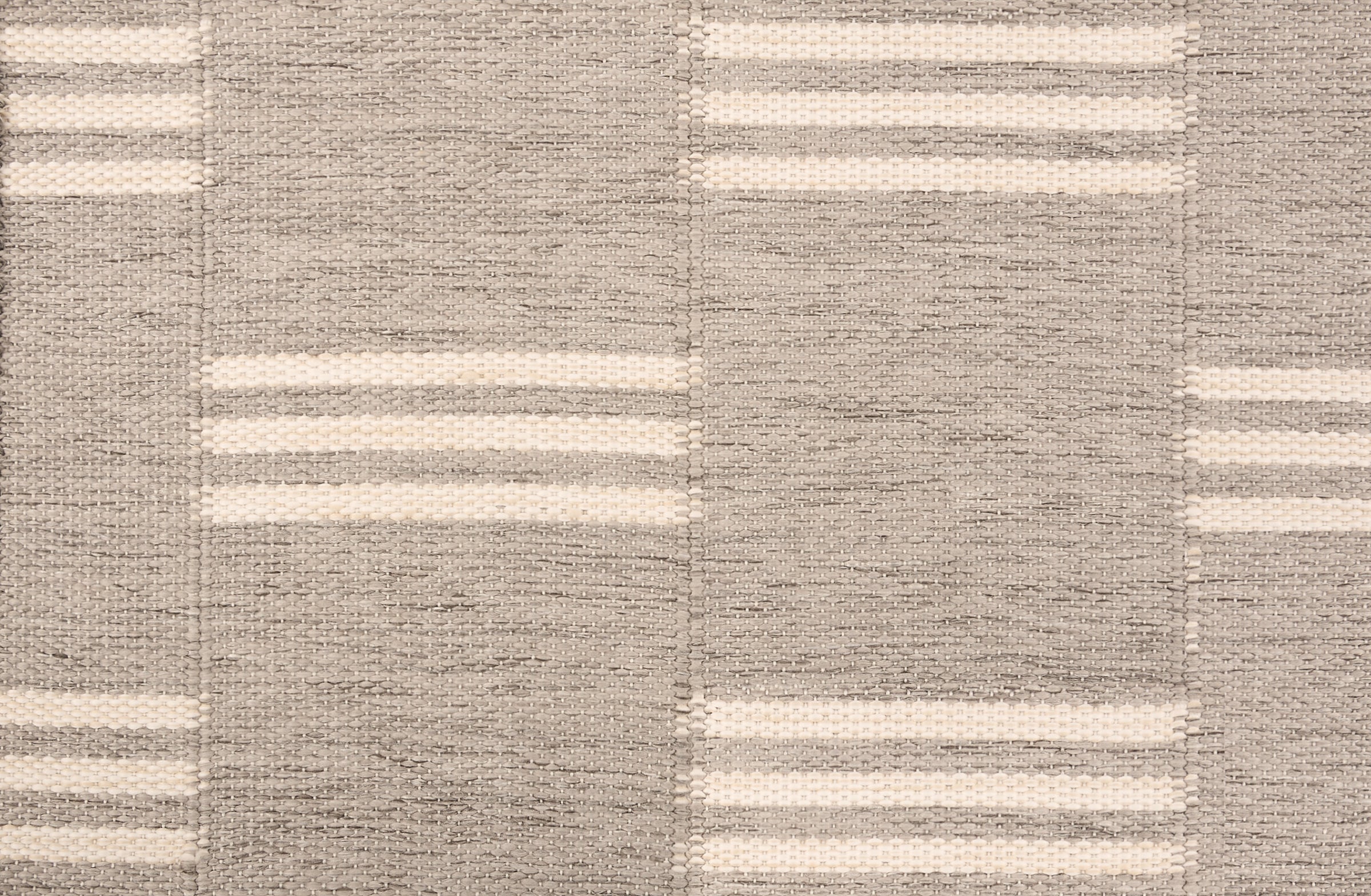Broadloom flatweave carpet in a broken stripe in white on a grey field.
