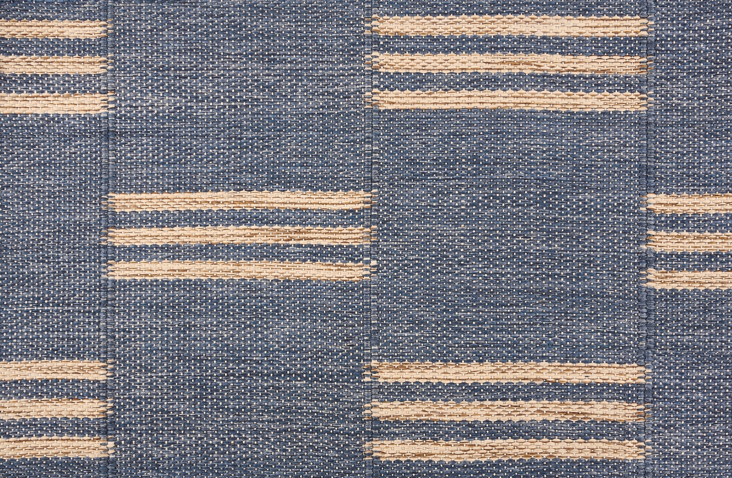 Broadloom flatweave carpet in a broken stripe in white on a blue field.