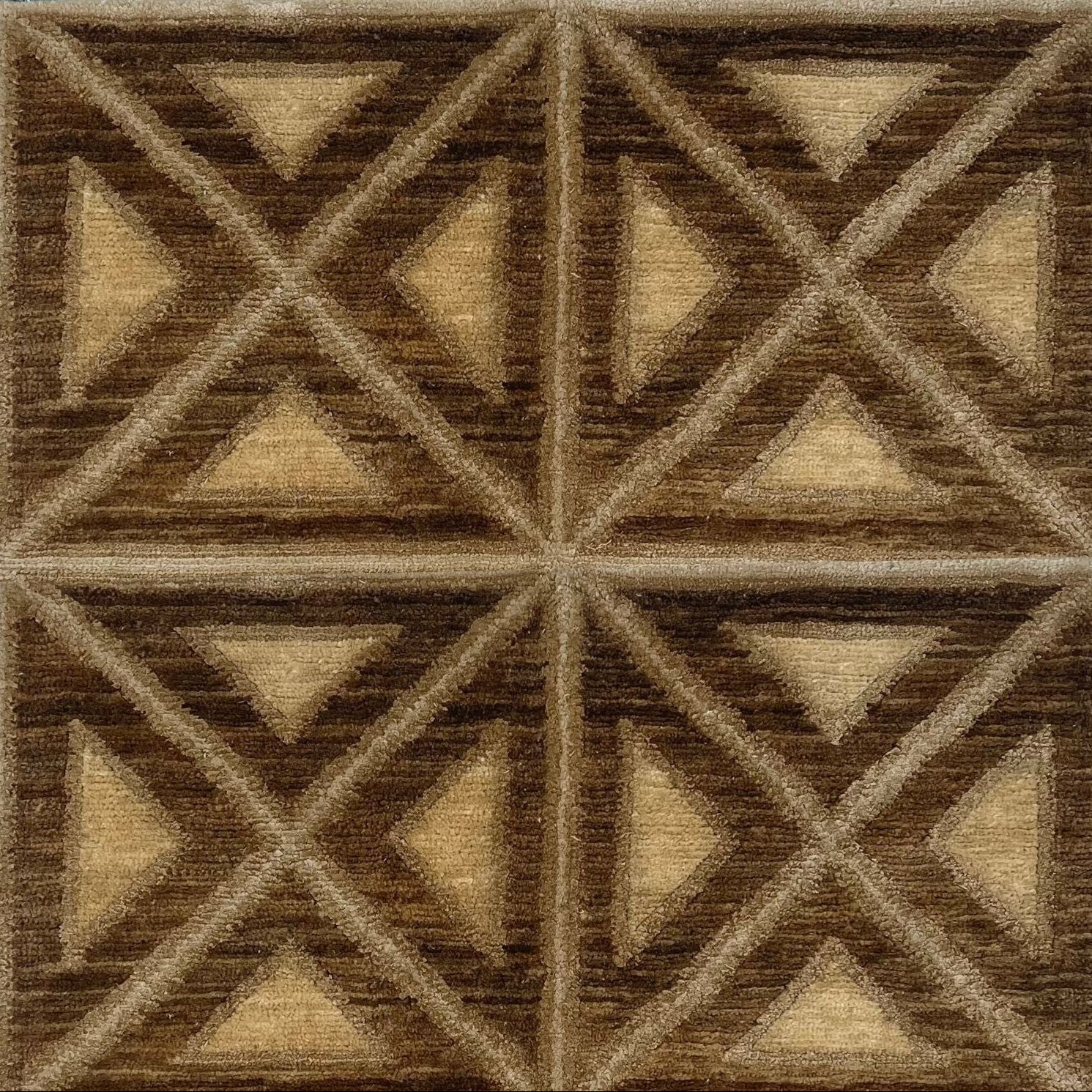 A rug woven in a repeating diamond and square pattern in brown, tan and beige.