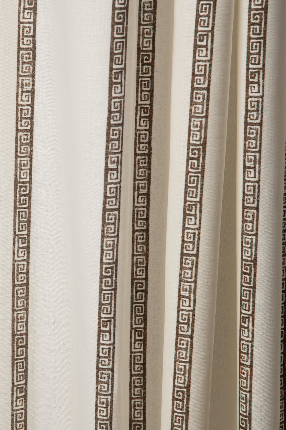 Draped printed fabric in a minimal geometric linear pattern in brown on a cream field.