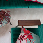 An overhead shot of teal velvet chairs with red and turquoise watercolor floral throw pillows.