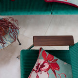 An overhead shot of teal velvet chairs with red and turquoise watercolor floral throw pillows.