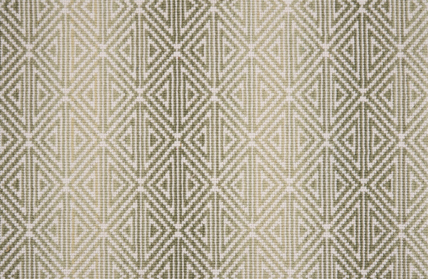 Broadloom carpet with triangle pattern with an ombré background in shades of green. 