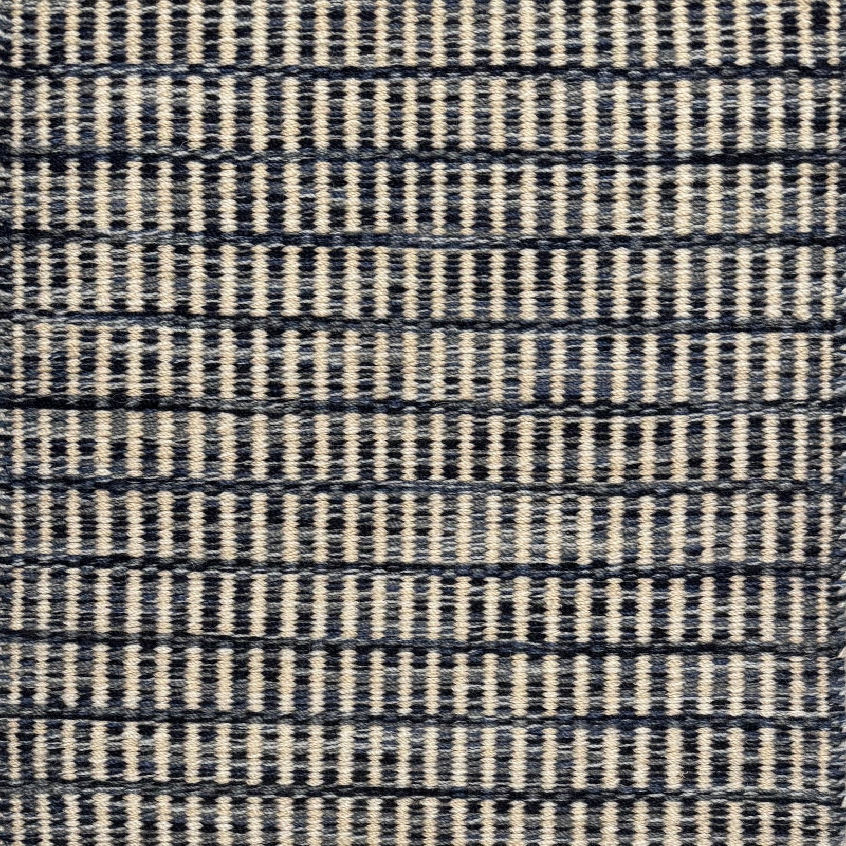 Textured rug with a striated navy blue and cream checker pattern