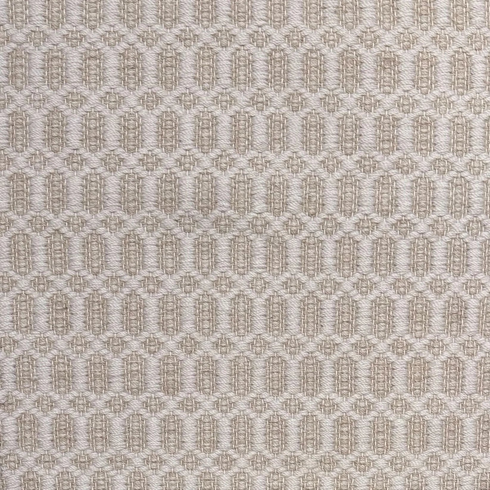Handwoven wool rug with an oval and diamond lattice pattern in shades of cream and beige. 