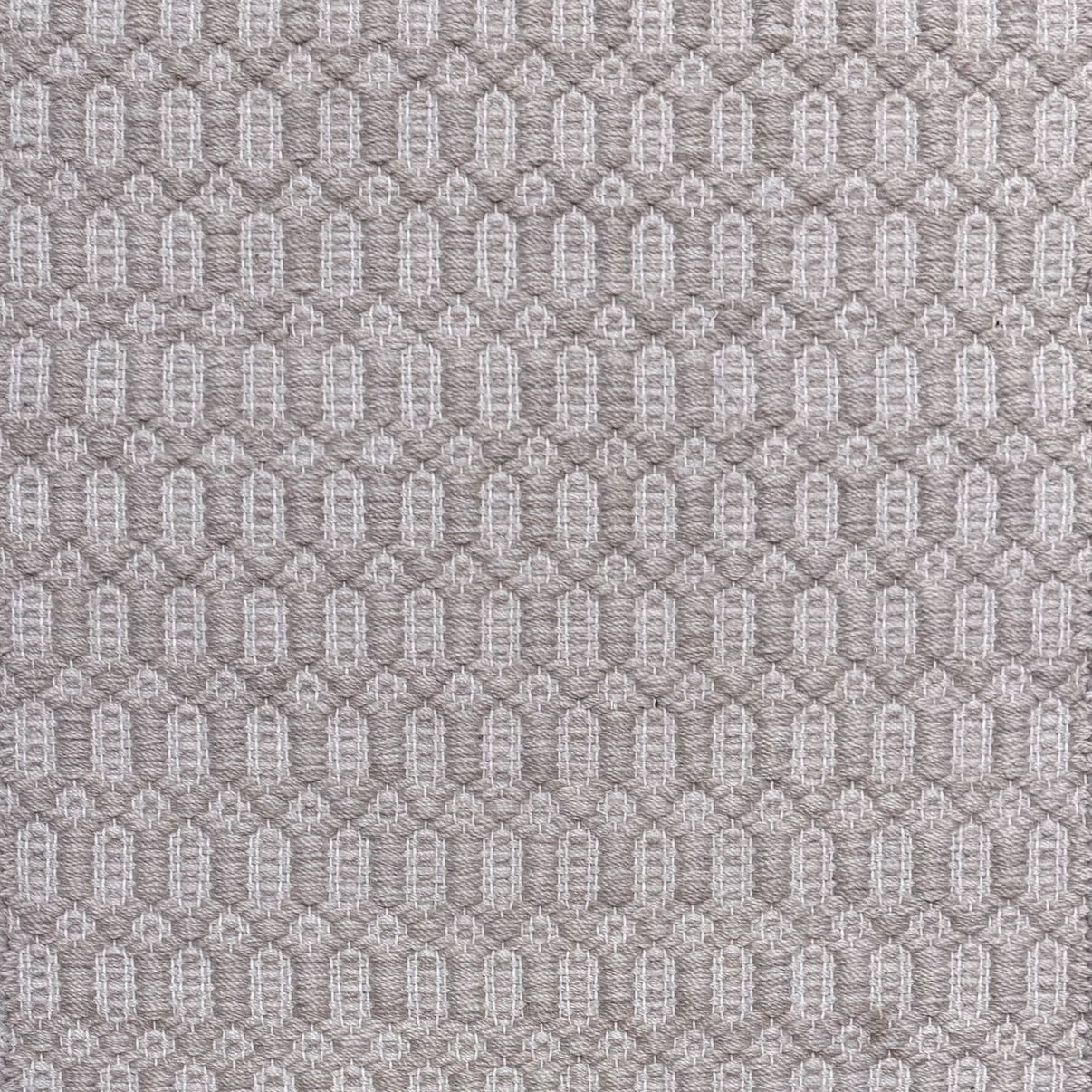 Handwoven wool rug with an oval and diamond lattice pattern in shades of grey and taupe.