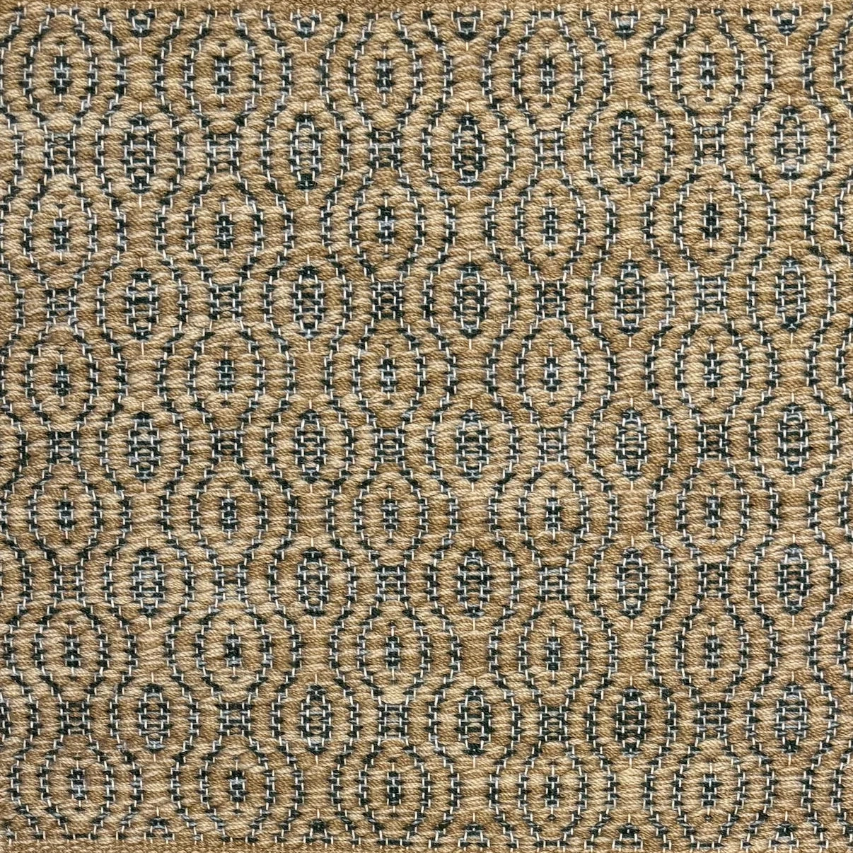 Handwoven wool rug with undulating oval stripe in shades of tan on a charcoal grey field. 