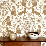 Detail of wallpaper in a lion and plant print in brown on a white field with  wooden table and ceramic vessels. 