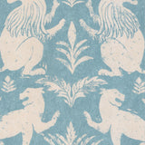 Close-up of fabric in a lion and plant print in cream on a light blue field.