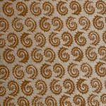 Detail of fabric in a repeating curved leaf print in white and brown on a tan field.