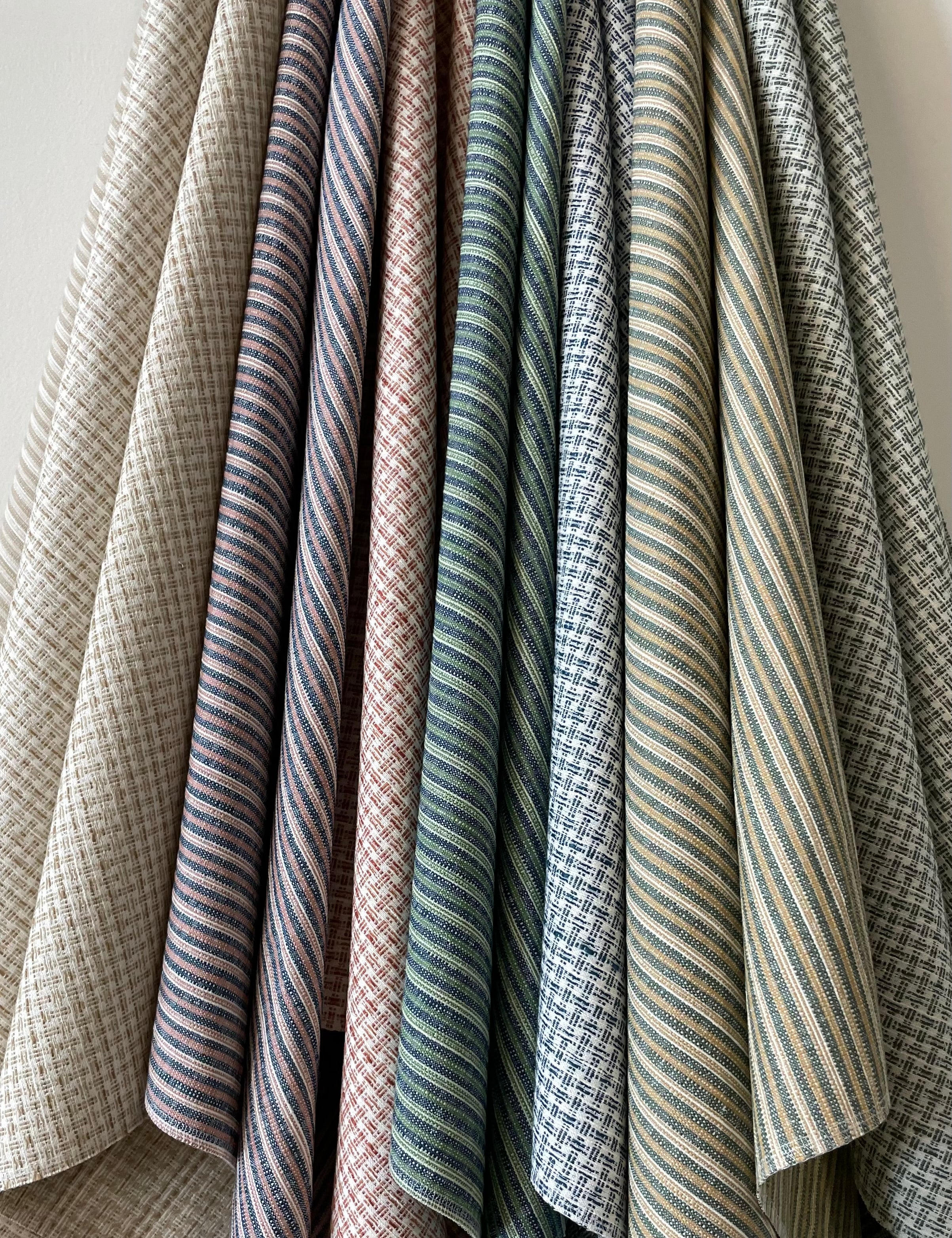 Set of hanging fabric swatches in stripe and plaid designs in various colors. 