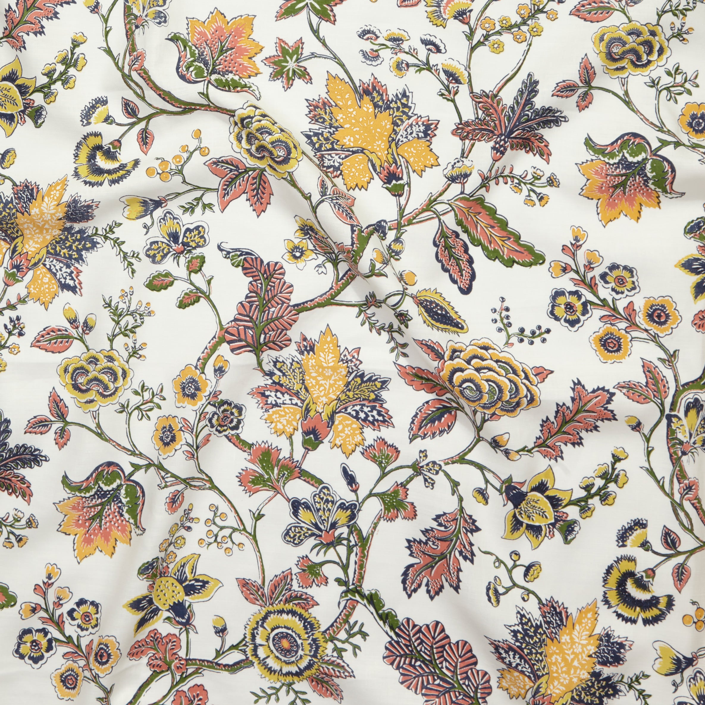 Close up of gently draped printed fabric in scrolling floral vine pattern in yellow, clay pink, orange, navy blue and olive green on white. 
