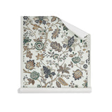 Roll of wallpaper in scrolling floral vine pattern in dark green, navy blue, tan and brown on white. 