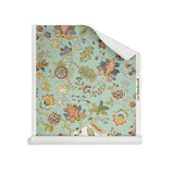 Roll of wallpaper in scrolling floral vine pattern in yellow, orange, navy blue and olive green on sea foam green.