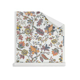 Roll of wallpaper in scrolling floral vine pattern in yellow, clay pink, orange, navy blue and olive green on white. 
