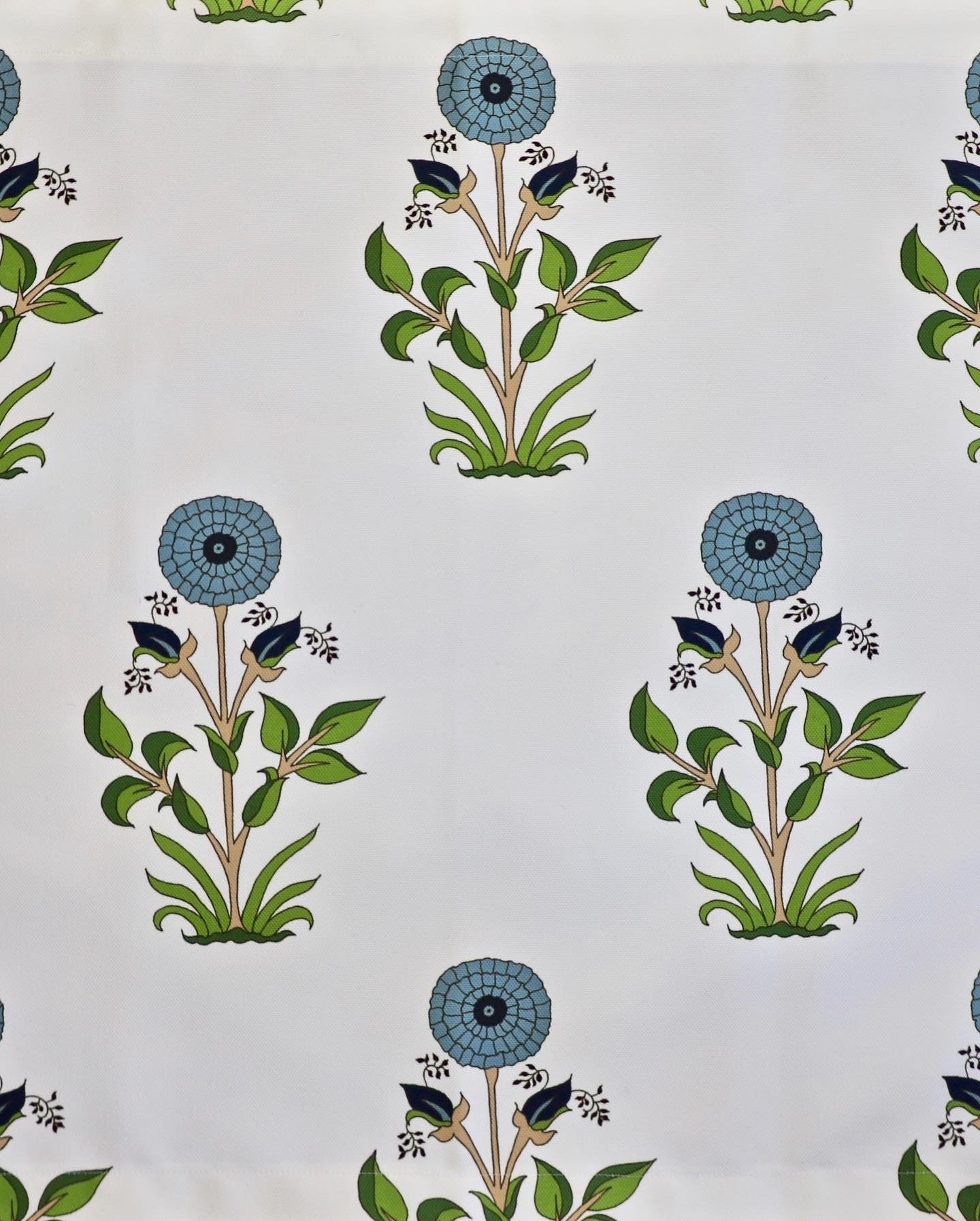 Detail of fabric in a large-scale marigold print in blue, orange and green on a white field.