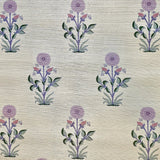 Detail of fabric in a large-scale marigold print in purple, pink and green on a tan field.