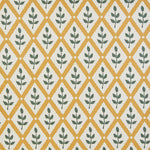 Detail of fabric in a lattice and leaf print in green and yellow on a white field.