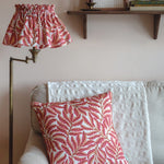 Living room with a sofa, pink leaf-patterned pillow, and matching lampshade.