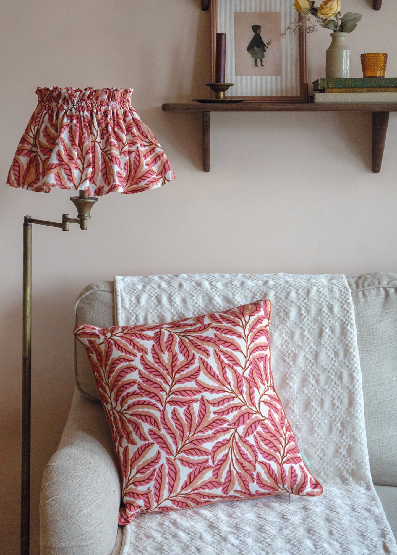 Living room with a sofa, pink leaf-patterned pillow, and matching lampshade.