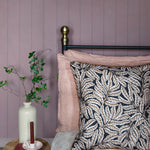 Bedroom with pale purple walls, floral-patterned pillow, and small round table with a vase and books.