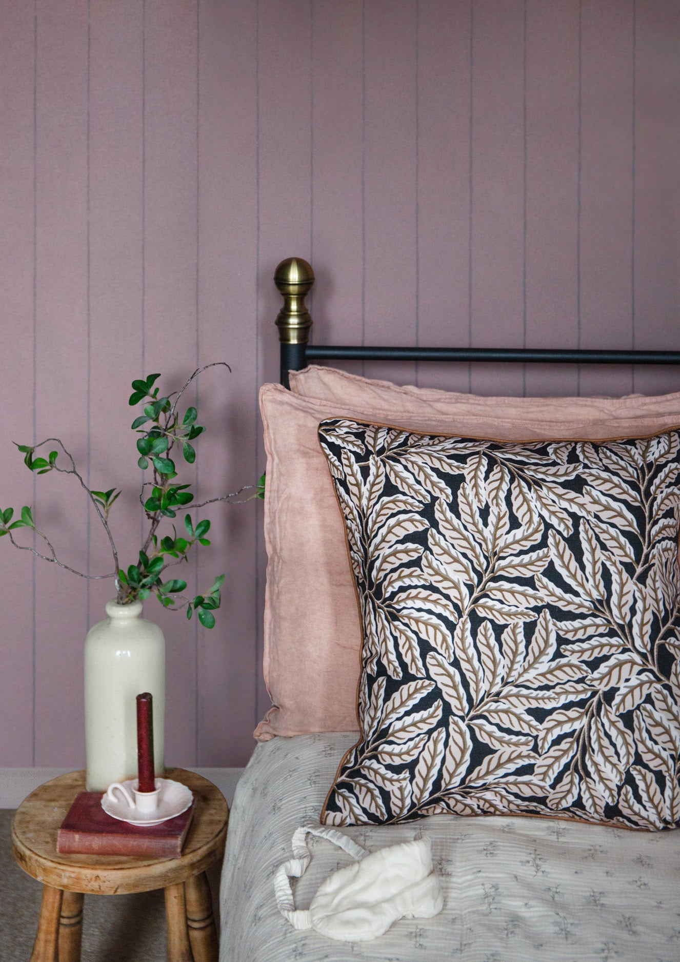 Bedroom with pale purple walls, floral-patterned pillow, and small round table with a vase and books.