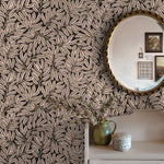 Room interior with leaf-patterned wallpaper, a round mirror, and decorative items.