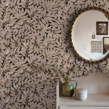 Room interior with leaf-patterned wallpaper, a round mirror, and decorative items.