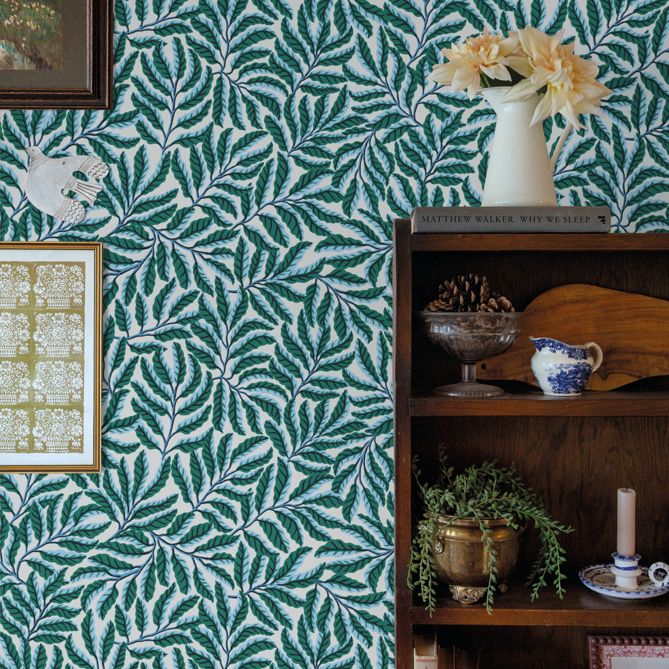 Room interior with green leaf-patterned wallpaper, bookshelf, and decorative items.